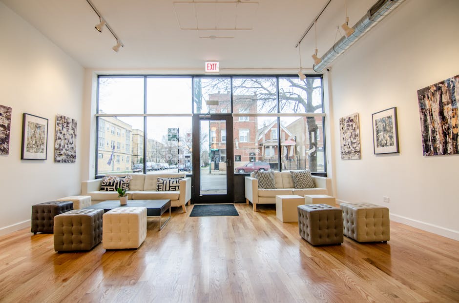 Contemporary art gallery interior with large windows, stylish seating, and view of urban street.