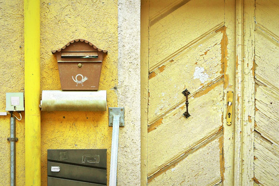 Rustic exterior featuring a weathered yellow door and vintage mailbox.